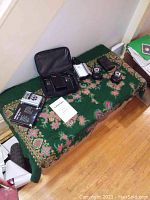 Photo of various electronic items on green patterned fabric including portable radio, walkie talkies with docking station, and mini recorder.