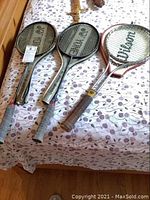 Photo of two Yonex badminton rackets and one Wilson tennis racket placed on a floral-patterned tablecloth, showing overall condition and grips.