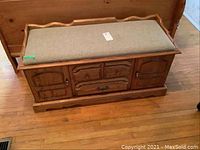 Pine upholstered bench chest from the front, showing cushioned top, two cabinet doors, and three drawers.