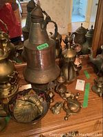 Overview of large metal pitcher surrounded by smaller pitchers and figures on wooden surface