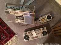 Overview of three portable stereo units on carpet: one Sony and two Sanyo