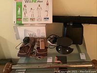 Overview photo showing Wii Fit Plus box, Wii console box, Clair OK muscle builder set, Polk Audio sound bar, and Philips speaker on a table.