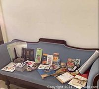 Wide view of all items arranged on a blue upholstered wooden couch, showing fans, guides, figurines, sake set, and stationery.