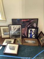 Full view of all framed artworks arranged on floor, showing variety of sizes and subjects including landscapes, abstract art, and architectural photos.