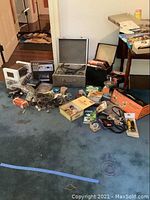 Overall shot of the lot showing multiple tape decks, cases, boxes, and audio accessories scattered on carpeted floor.