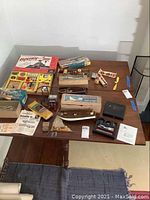 Overview of assorted vintage model kits, boat, plane parts, and an electric build-it set on a table, showing original packaging and assembled items.