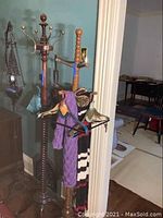 Two wooden coat racks side by side with hanging umbrellas, decorative hangers, and scarves