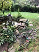 View of three flat trellis panels and one domed trellis on stone and grass ground with plants around