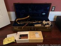 Open hard case with alto saxophone and cleaning kit on floor