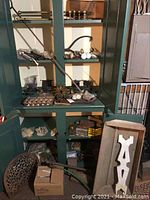 Shelf and cabinet with assorted vintage hardware including brass knobs, door hinges, and metal pieces along with a wooden box.