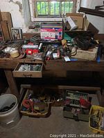 Wide view of wooden workbench with assorted hand tools, boxed Weller propane torch kit, small electrical accessories and cords below bench