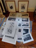 Multiple vintage prints and magazine pages laid out on a wooden floor showing different sizes and subjects including portraits and landscapes.