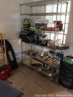 Photo showing full metal shelving unit with six wire grid shelves filled with various items (not included). Shelving rack has chrome finish with four wheels.