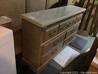 Side view of the light wood dresser showing faux marble top and drawer fronts with metal handles