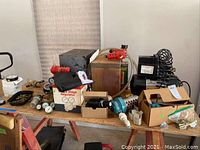 Wide view of wooden table containing air compressor, regulator, gauges, fittings, and accessories in boxes