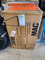 Photo of the cardboard box housing the MAC push reel mower showing product branding and label.