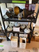 Shelf with assorted indoor dome lights, speakers, and boxed outdoor motion-sensing lanterns