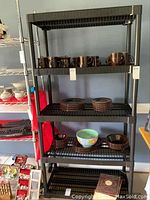 Two matching black plastic shelving units with ventilated shelves, some shelves shown with dishes (not included). Units are tall with five shelves each.
