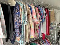 Photo showing ladies shirts on hangers with various floral, plaid, and colorful patterns.