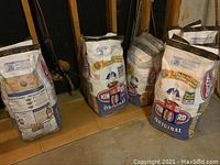 Photo showing multiple unopened white bags labeled Kingford Original charcoal.
