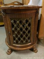 Full view of the round wooden side table with metal lattice door and claw feet