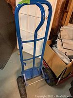 Full view of blue metal hand truck showing tubular steel frame, curved handle, and flat nose plate.