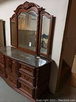Full view of dresser base with marble top and attached triple mirror against basement wall