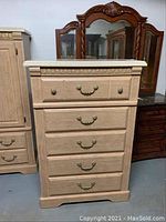 Front view of a four drawer chest of drawers showing light wood finish with brass handles.