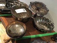 Silver plated silverware items including compote pedestal bowl, flower bowl with frog figurine, footed bowl with squirrel motif, and additional bowls and trays showing overall condition.
