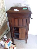 Full front view of wooden Columbia Grafonola cabinet with hinged lid closed, glass platter cover and decorative top accents