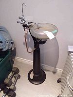 Full view of vintage dentist sink with black pedestal and frosted glass basin, showing faucet assembly and hose attachment.