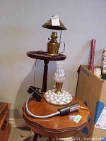 Three lamps displayed on wooden side tables, including a brass lamp with brown shade, a white textured glass lamp, and a black flexible clamp lamp.