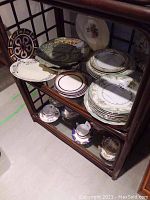 Shelf with multiple Noritake china plates, platters, and teacups arranged