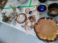 Multiple silver plated tableware items arranged on a table including bowls, shakers, napkin rings, and serving dishes.
