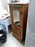 Front view of oak cabinet showing mirrored door and lower drawers