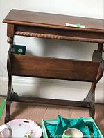 Front view of wood side table showing flat top, lower rack panel, and carved twisted apron with ball finials.