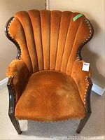 Front view of vintage orange velour upholstered chair with fan back and nailhead trim