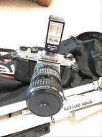 Pentax K1000 camera with Takumar-A Zoom lens and Minolta Auto-EL flash on top, resting on Optex tripod.