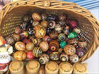 Wicker basket overflowing with hand-decorated pysanky eggs in various colors and patterns
