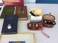Full view of items on table showing opera glasses, books, small mask, and a framed item.