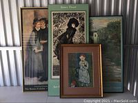 Four framed art prints and posters standing against a wall. Titles include 'James Tissot' and The Barnes Exhibit. Frames vary in size and style.