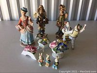 Wide view of entire lot showing Boyds Bears, dancers, floral porcelain pieces, and bunny figurines arranged on white surface.