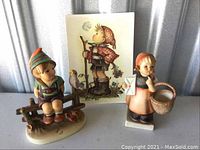 Front view of both Hummel figurines and vintage style card showing boy figure illustration