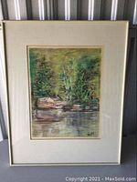 Full view of framed landscape art showing trees by water with rocks, featuring a white matte and simple frame.