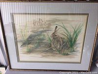 Full view of framed art showing rabbit sitting by water with reeds and grasses.