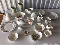 Full view of the lot showing multiple items including plates, bowls, pitchers and mugs, arranged on a table.