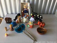 Wide view of assorted animal and decorative figurines with wooden bowl and pestle and kitchen tongs