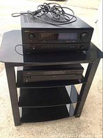 Full view of the Denon audio components on the black stand showing the receiver, CD changer, and stand with cables on top.