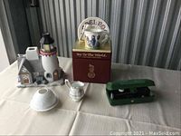 Photo showing Royal Doulton lighthouse piece, Royal Albert creamer, vintage Singer sewing machine in green case, and quilt boxed in red.