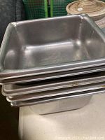 Stack of five rectangular metal food server pans measuring approximately 6x7 inches each.
